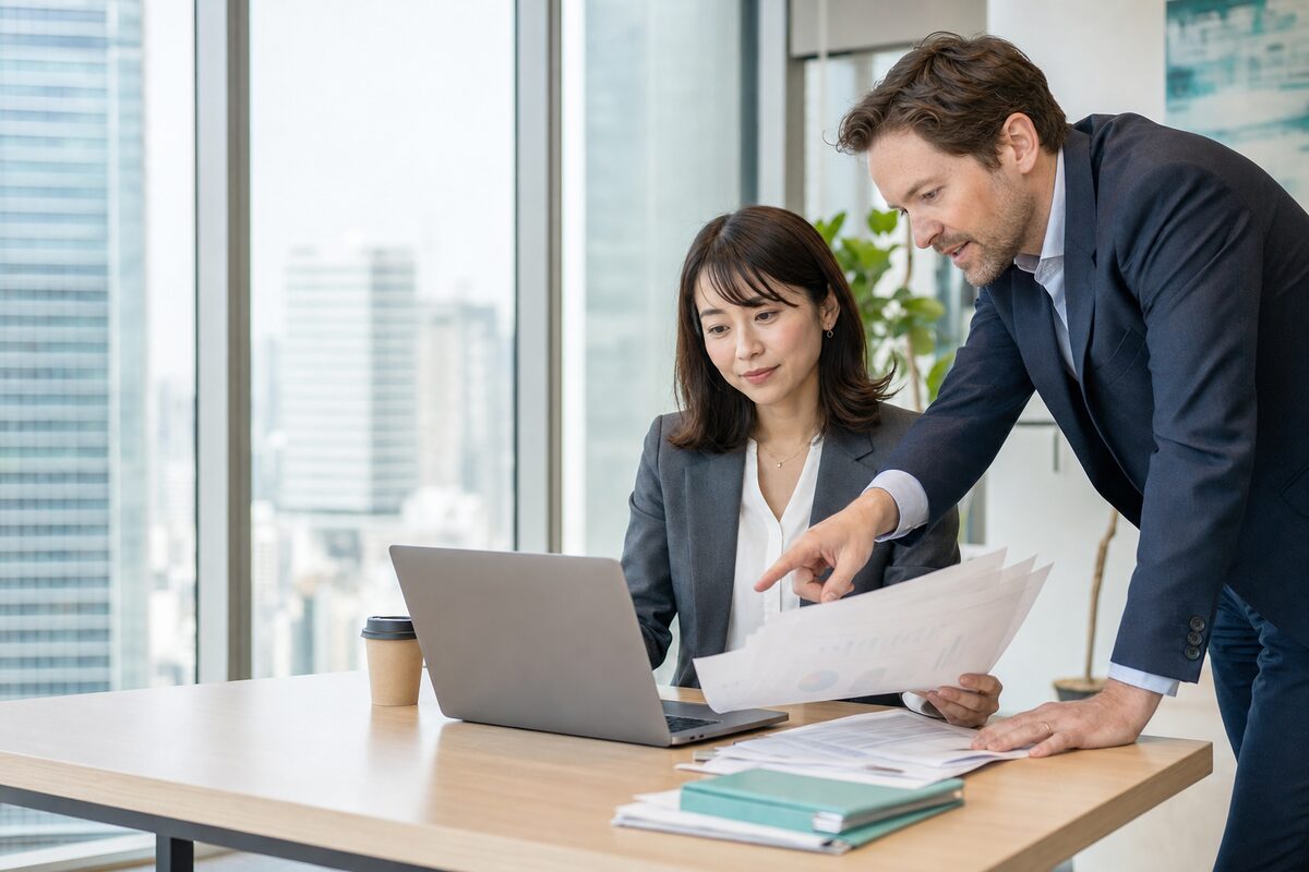 A payroll specialist reviewing payslips with a colleague in a Tokyo office
