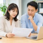 Two colleagues in a Japanese office reviewing a payslip together